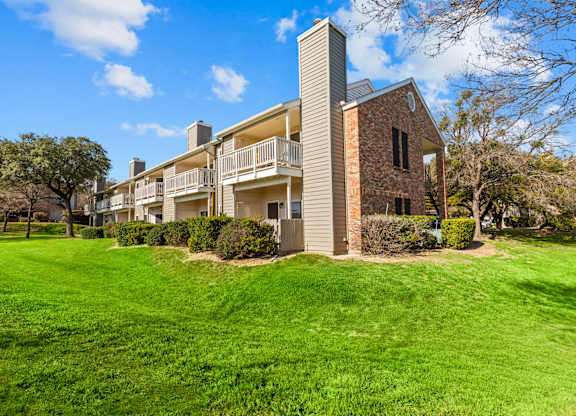 A large grassy area in front of a building with a balcony.
