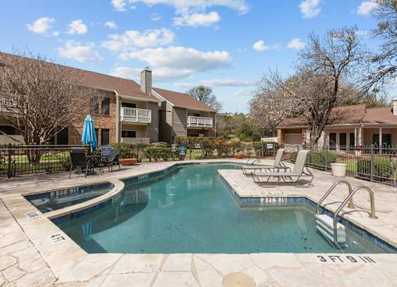 A swimming pool surrounded by a fence and chairs.