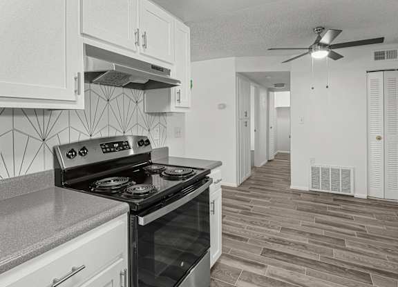 an empty kitchen with white cabinets and a black stove