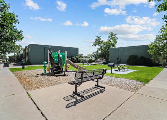 a park with a playground and benches in front of a building