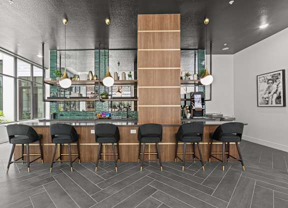A modern bar with black chairs and a wooden counter.