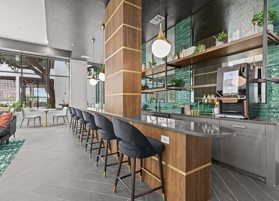 A modern bar area with a long wooden bar and black bar stools.