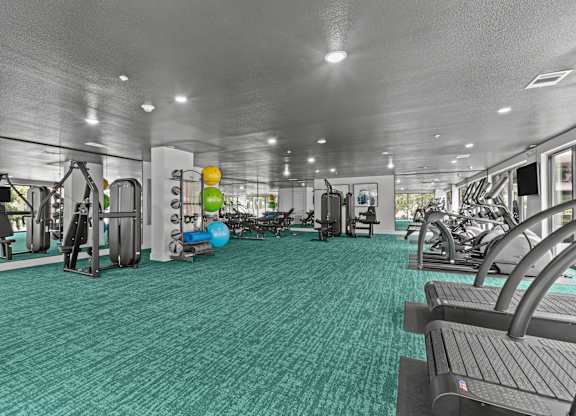 A gym with a variety of equipment including treadmills, weights, and exercise machines.