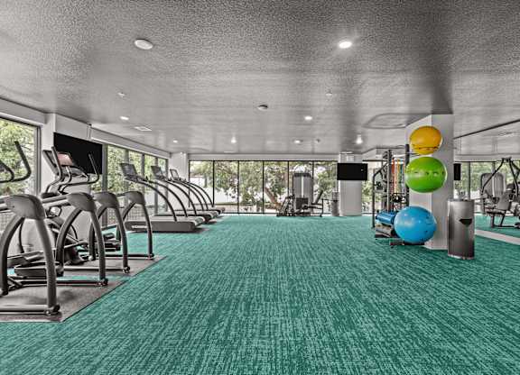 A gym with a green carpet and various exercise equipment.
