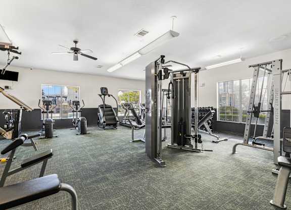 A spacious gym with a variety of equipment including treadmills, weights, and a bench.