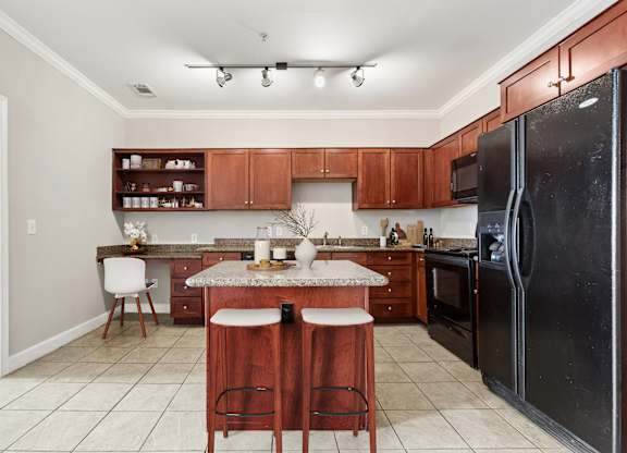 A kitchen with a black refrigerator and wooden cabinets.