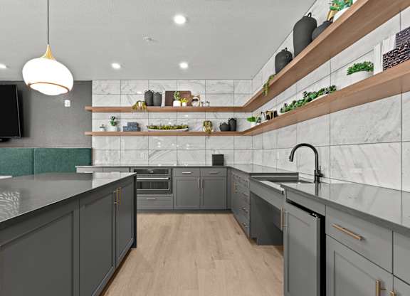 A modern kitchen with dark grey cabinets and a wooden shelf above the counter.