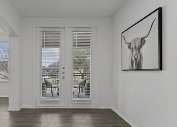 A black and white painting of a bull head hangs on a white wall above a white door.