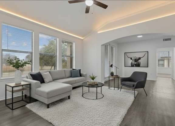 A living room with a grey sofa, a black chair, and a white rug.