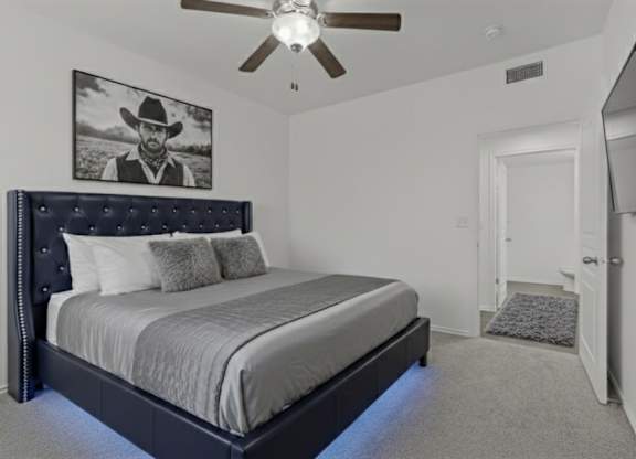 A bedroom with a large bed and a ceiling fan.