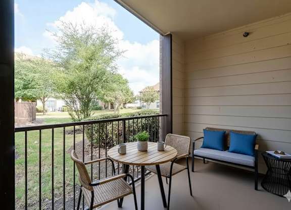 A balcony with a table, chairs, and a sofa.
