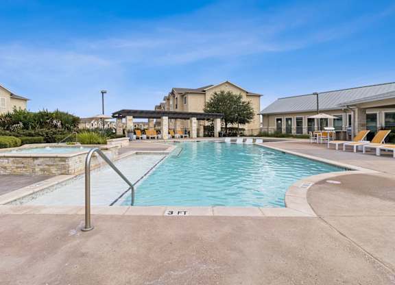 A swimming pool with a metal ladder and a building in the background.