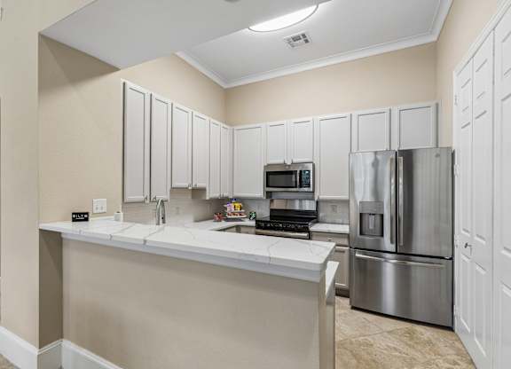 A kitchen with a white counter and stainless steel appliances.