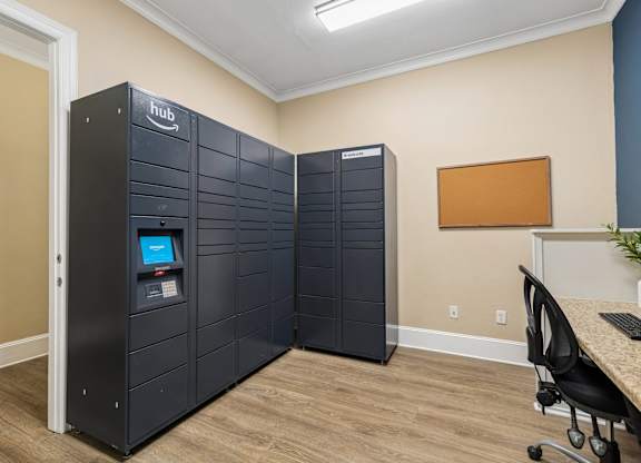 A room with a computer desk and two tall black cabinets with a logo on the front.