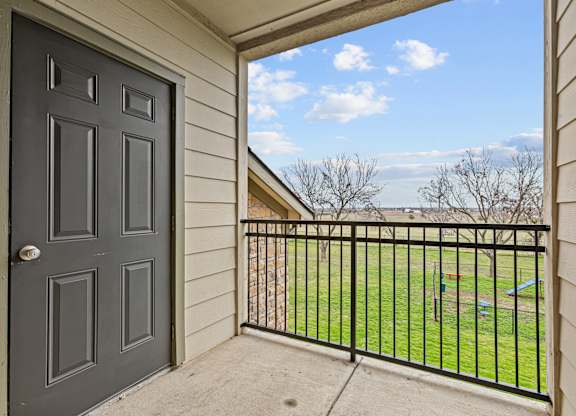 A view from a doorway looking out to a fenced yard.