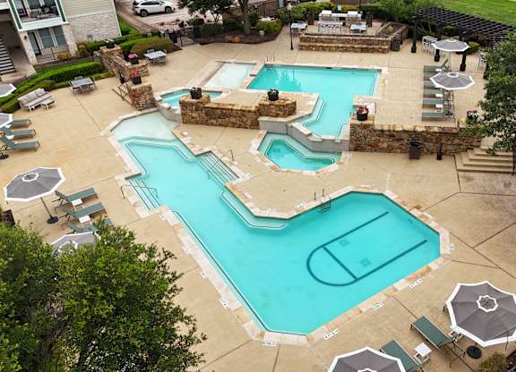 a pool and spa are shown in a backyard with tables and umbrellas