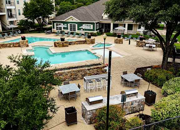 an aerial view of a pool and patio with tables and umbrellas