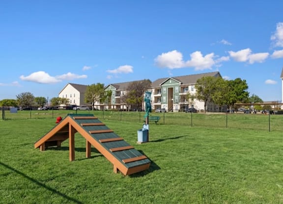 A playground with a slide in the middle of a grassy area.