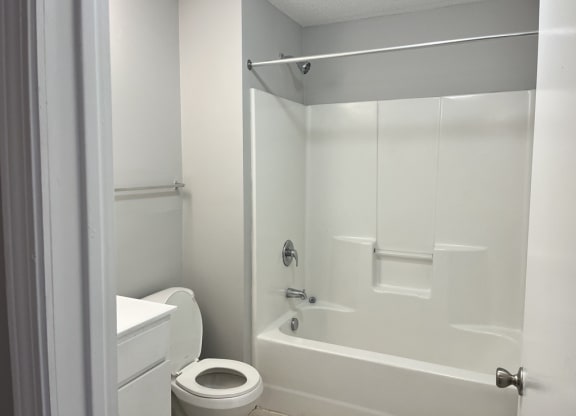 a white bathroom with a toilet and a tub and a sink