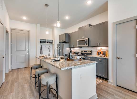 A kitchen with a white island and grey bar stools.