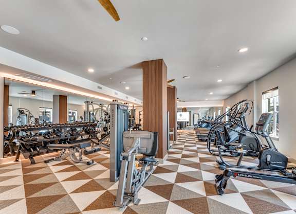 A gym with a variety of equipment including treadmills, weights, and exercise machines.