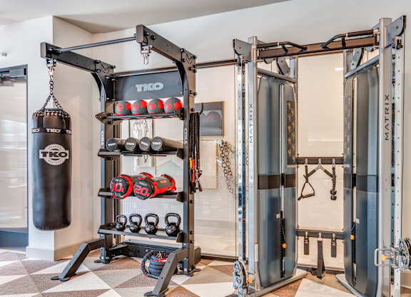 A black punching bag is hanging from a TKO branded hook in a room with a TKO branded wall.