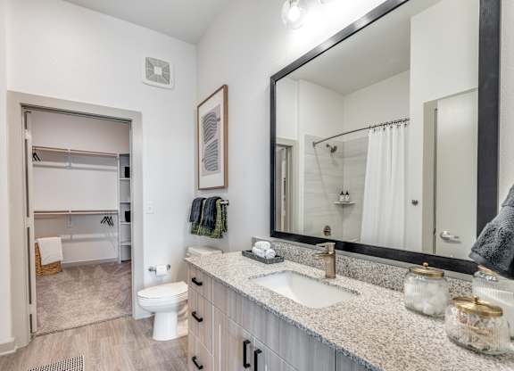 A bathroom with a white toilet, sink, and mirror.
