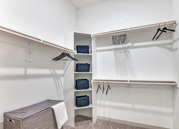 A white closet with clothes hanging and a brown box on the floor.