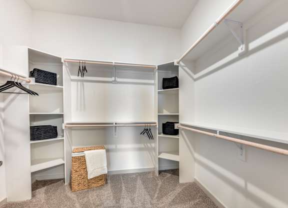 A white closet with a basket on the floor.