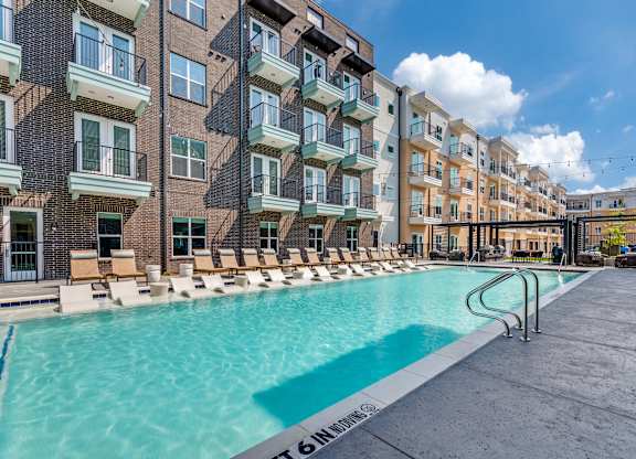 A swimming pool is surrounded by apartment buildings.
