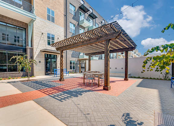 A patio with a table and chairs under a pergola.