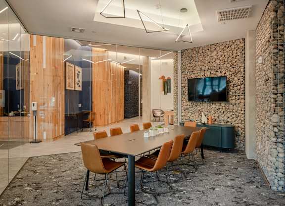 A conference room with a stone wall and a long table with chairs.