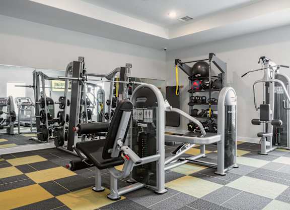 a spacious fitness room with weights and cardio equipment