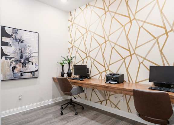 A room with a desk and a chair in front of a geometric wallpaper.