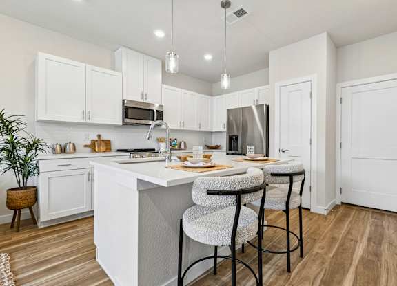 A kitchen with white cabinets and a wooden floor.