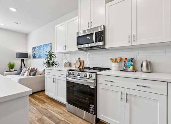 A modern kitchen with white cabinets and a black stove top.