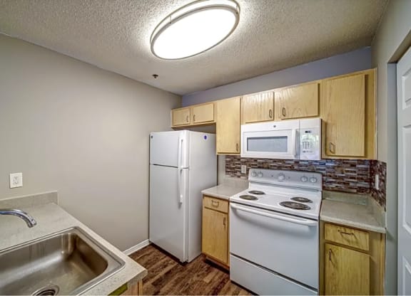a kitchen with white appliances and a sink and a refrigerator
