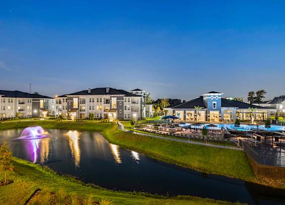 A beautiful view of a resort with a fountain in the middle of a lake.
