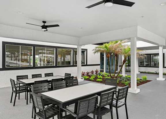 A patio with a table and chairs and a ceiling fan.