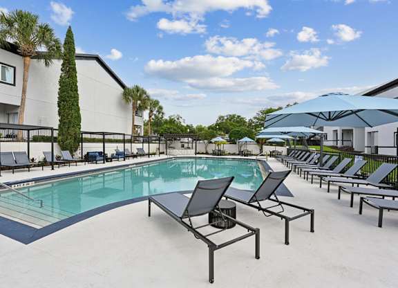 A pool with chairs and a building in the background.