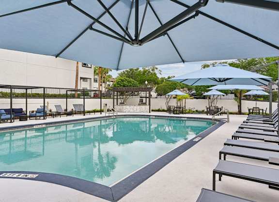 A large outdoor pool with sun loungers and umbrellas.