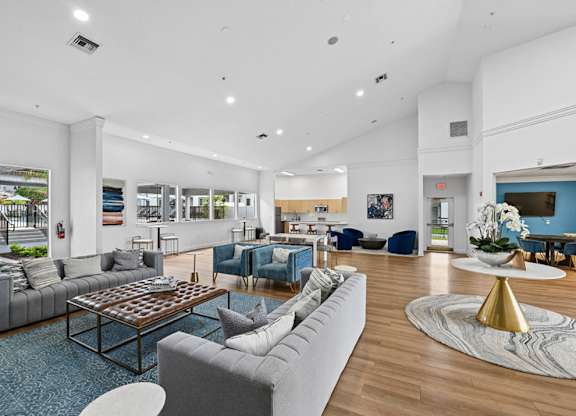 A spacious living room with a grey sofa, a coffee table, and a TV.