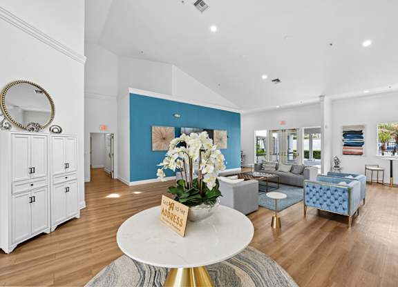 A living room with a white coffee table and a vase of white flowers on it.