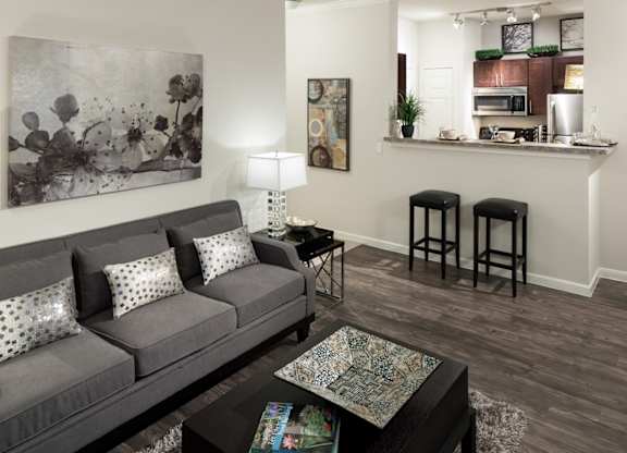 A grey couch with white pillows sits in a living room with a coffee table in front of it.