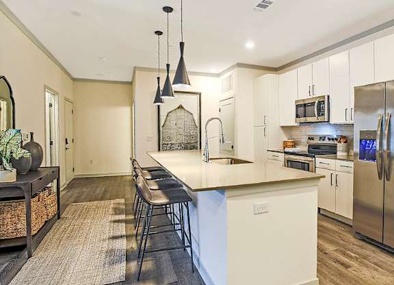 A kitchen with a white island and stainless steel appliances.