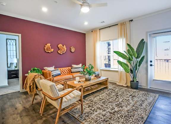 A living room with a sofa, chair, and potted plants.