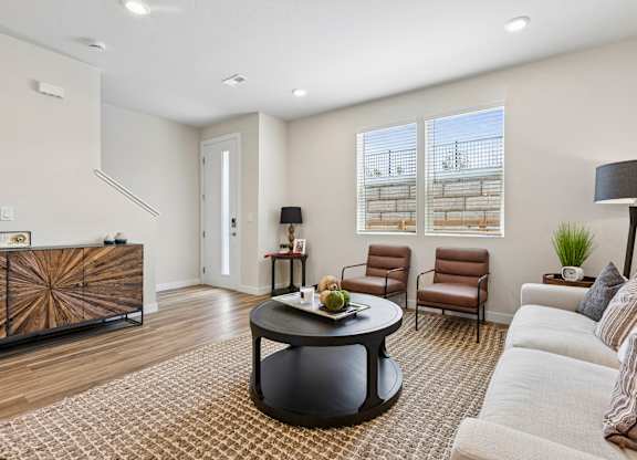 A living room with a brown and white patterned rug, a black coffee table, a white sofa, and a wooden cabinet.