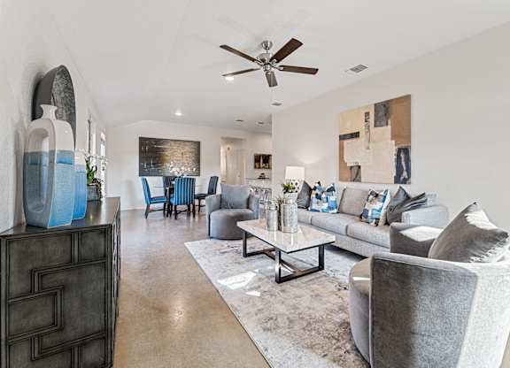 a living room with couches and chairs and a ceiling fan