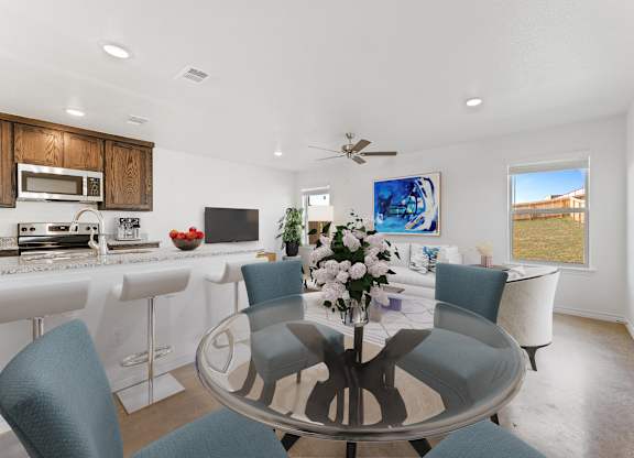 a dining room with a glass table and chairs and a kitchen with a counter top
