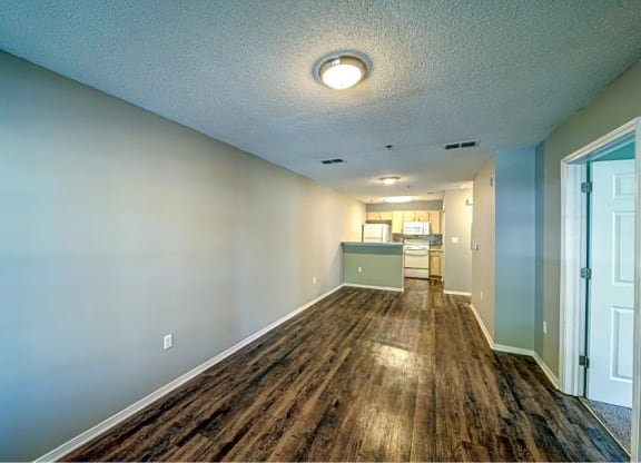 a long hallway with a wood floor and a kitchen